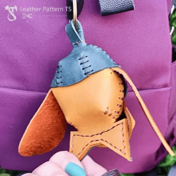DIY leather dog charm hanging on purple backpack side view with stitched details